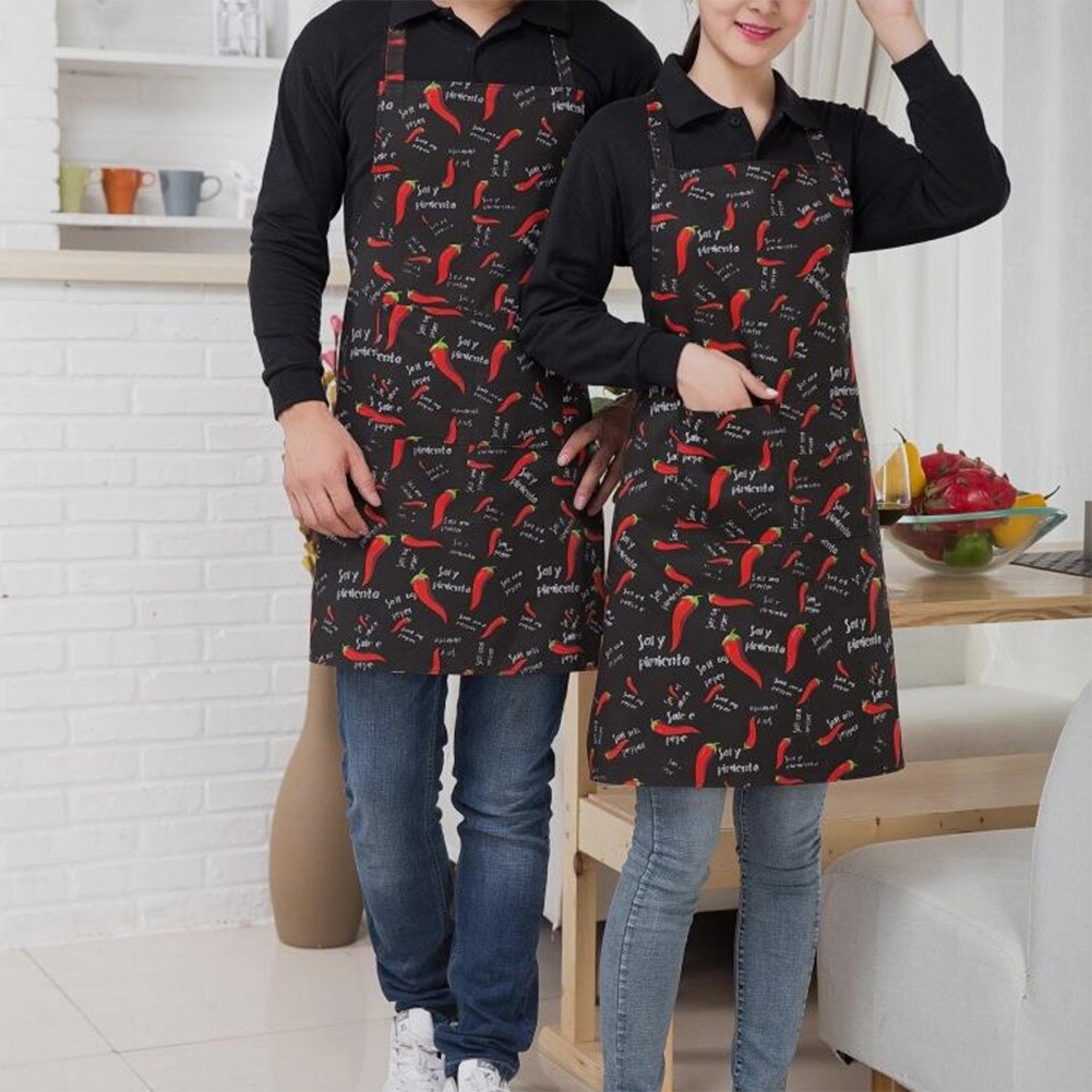 Two people in chilli print halter aprons cooking together at home