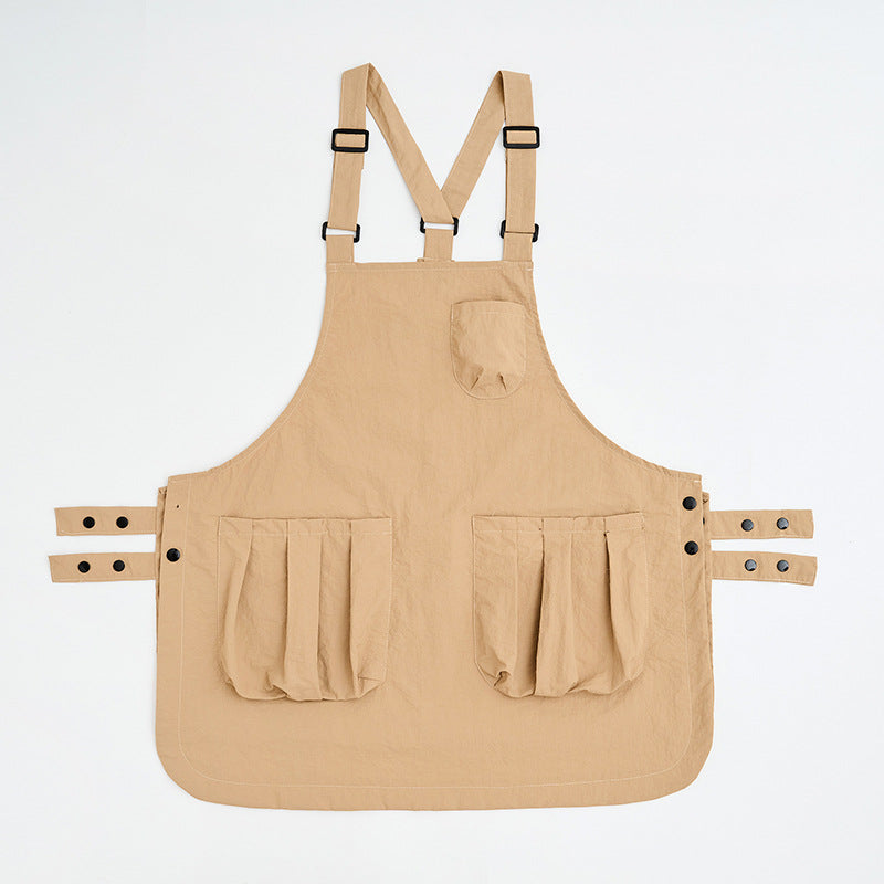 Khaki sleeveless kitchen apron laid flat showing its simple cut