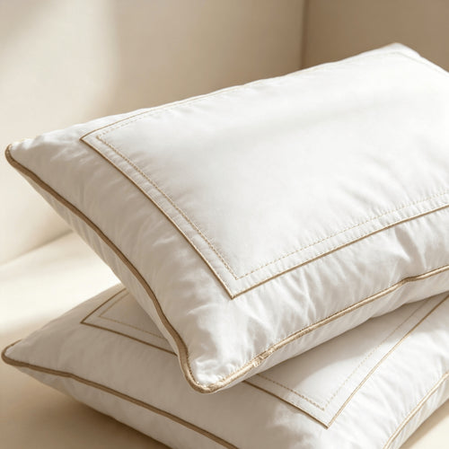 Two thick white all-season hotel pillows stacked on a plain background