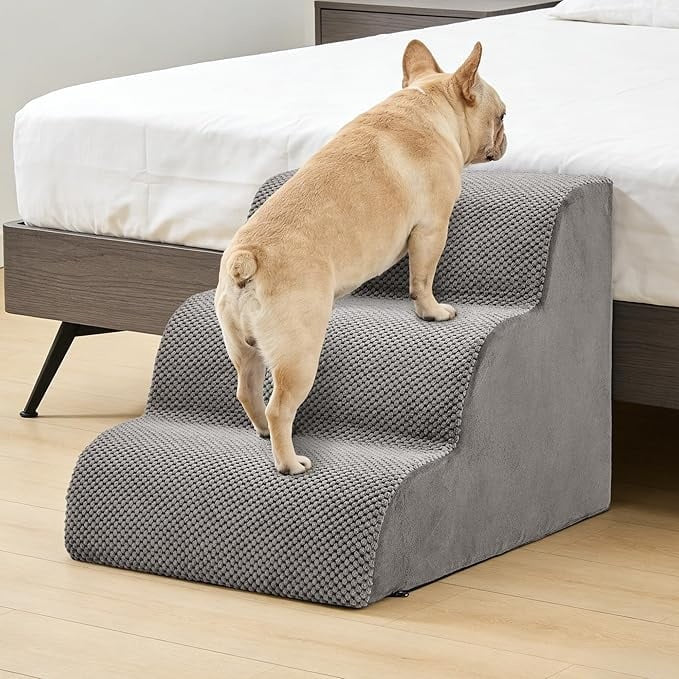 Small dog climbing grey high-density foam pet stairs beside a bed