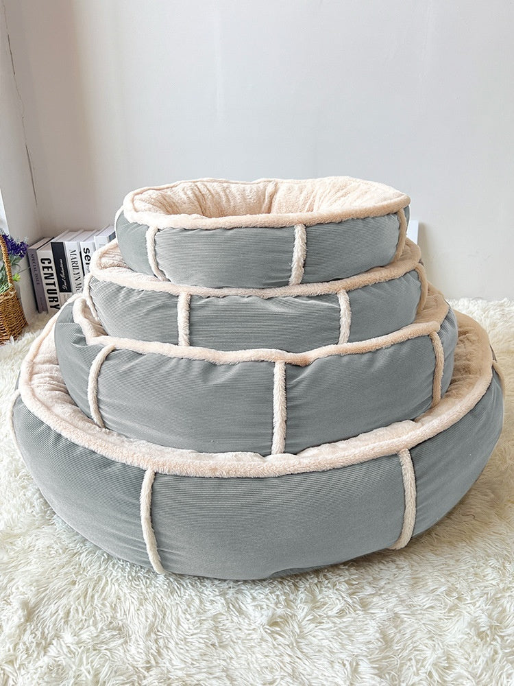 Grey round pet bed photographed outdoors on a sunny lawn