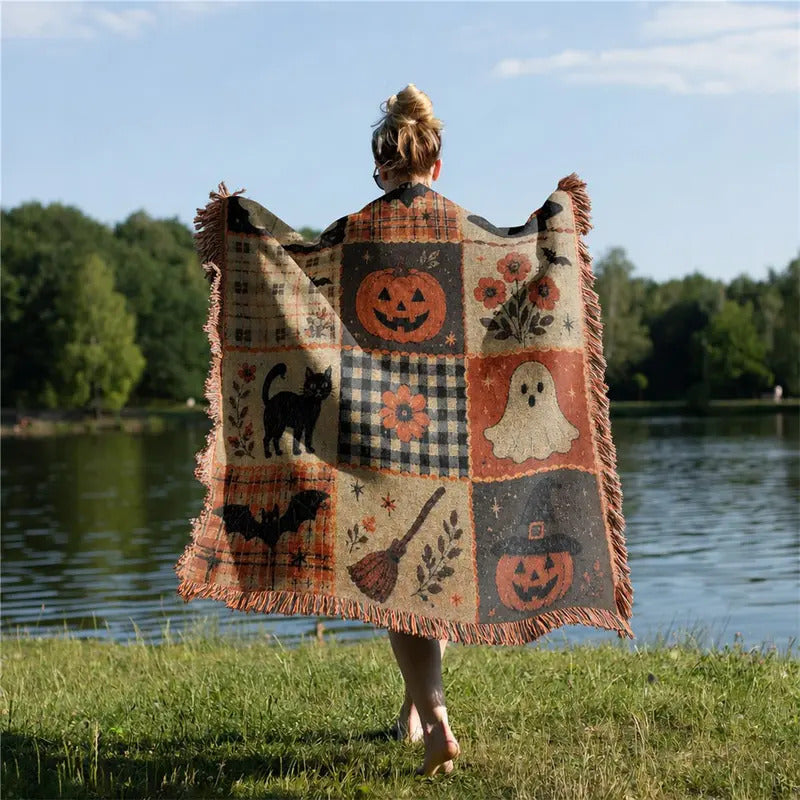 Person wrapped in the Halloween patchwork blanket outdoors by a lake