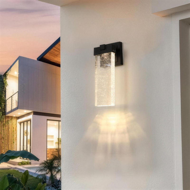 Outdoor crystal wall sconce glowing on a modern white exterior at dusk