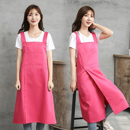 Two people wearing rose red cross-back aprons in a studio setting