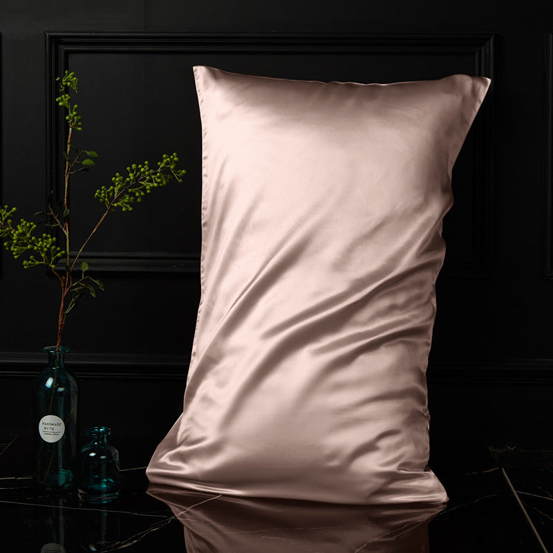 Blush pink silk envelope pillowcase with soft sheen in a moody bedroom