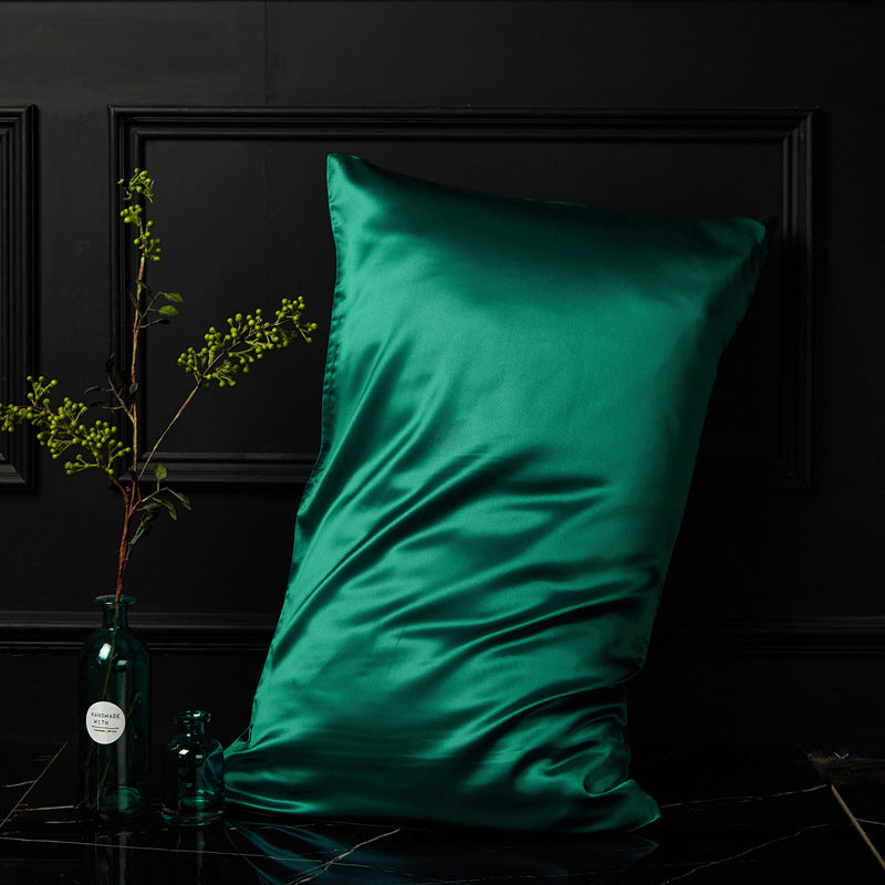 Emerald green mulberry silk envelope pillowcase catching light against dark panelled wall