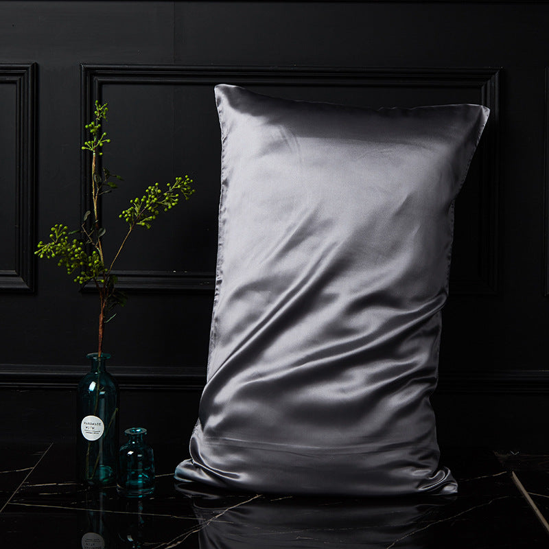 Metallic gray mulberry silk envelope pillowcase resting on a dark marble nightstand